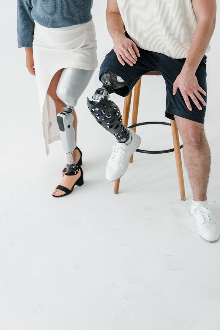 Two adults with prosthetic legs captured in a studio setting, highlighting technology and diversity.